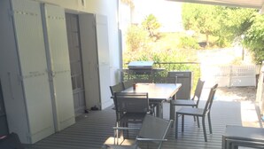 Un patio al aire libre con mesas, sillas, una parrilla y un acceso cubierto.