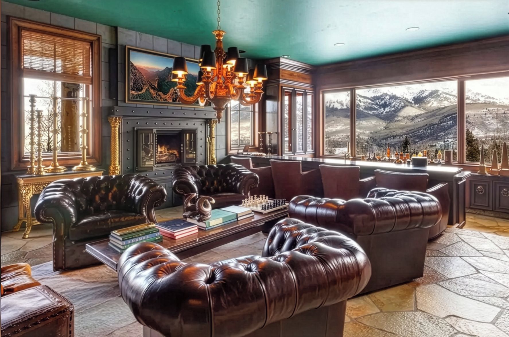 A luxurious living room with a fireplace, leather sofas, a coffee table with books, and a large window offering a mountain view.
