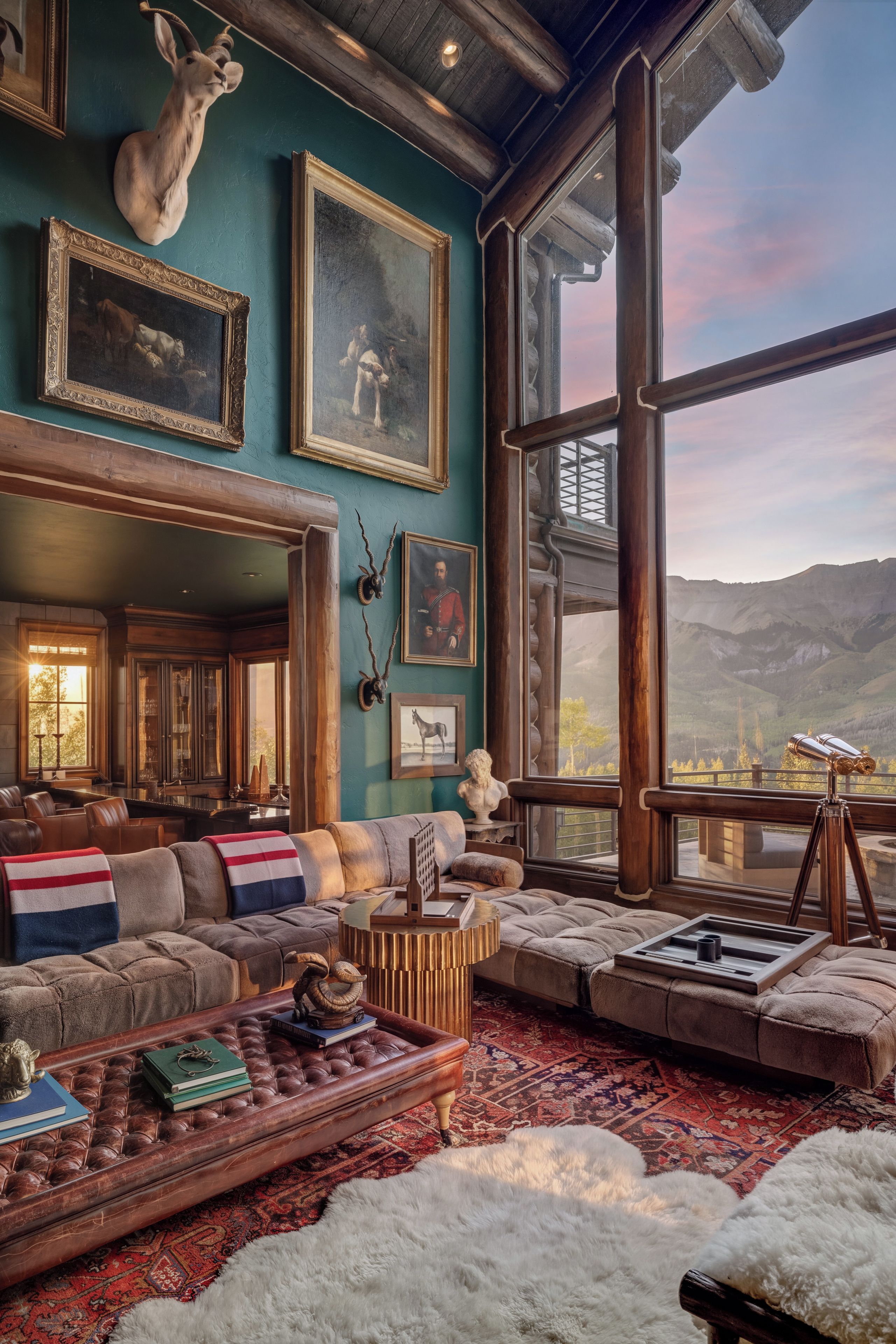 A spacious living room with a large window, leather sofas, a coffee table, and various decorative items.