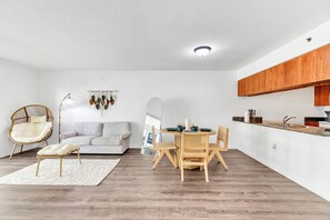 Ein zeitgemäßer Wohnbereich mit Sofa, Esstisch, Stühlen und einer Küchenzeile.