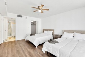 Ein Hotelzimmer mit zwei Betten, einem Deckenventilator und Holzboden.