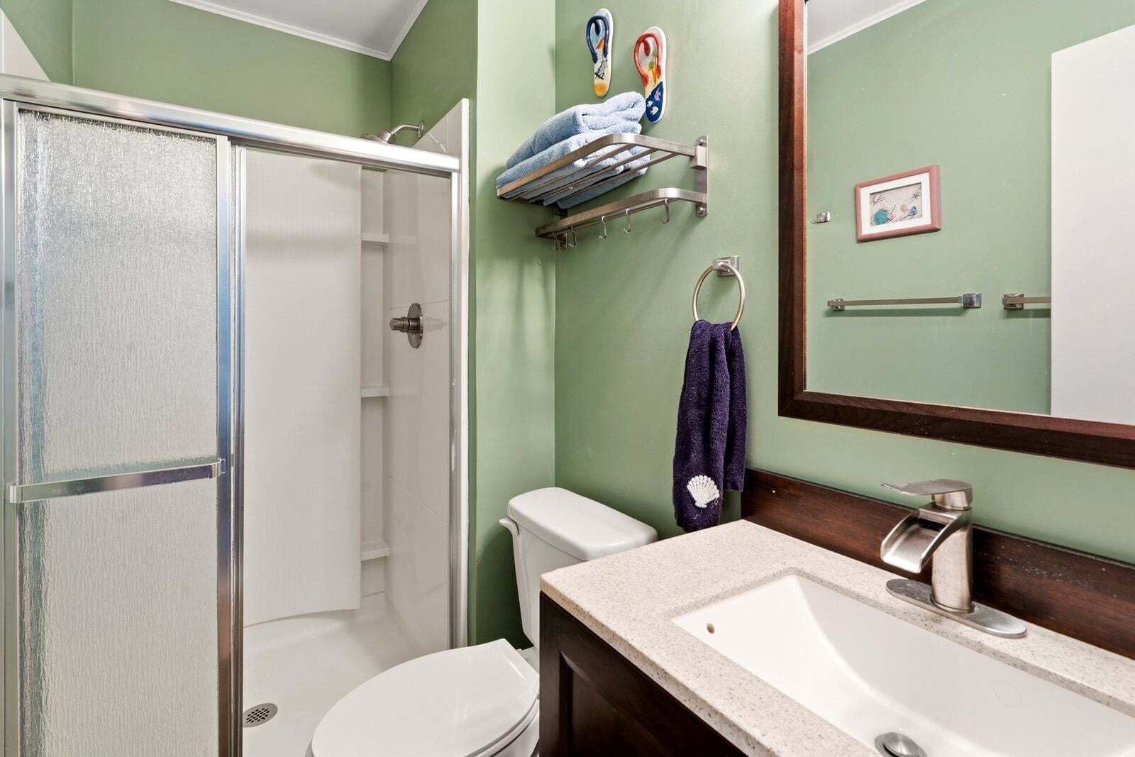 A bathroom with a shower, toilet, sink, and towel rack.