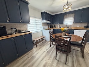 Una cocina moderna con armarios oscuros, una mesa de comedor de madera y un horno empotrado.