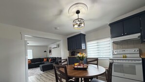 Une cuisine moderne avec des meubles de couleur sombre, une cuisinière blanche et un coin repas comprenant une table et des chaises en bois.