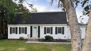A white house with black shutters, a front porch, and a small garden. - Queens Way Retreat-12 Guests-Pet Friendly (Wells)