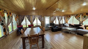 A wooden interior with a dining table, chairs, sofas, and a ceiling fan. - Queens Way Retreat-12 Guests-Pet Friendly (Wells)