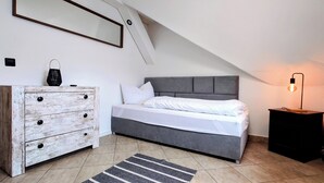A bedroom with a bed, a dresser, a nightstand, a lamp, and a mirror.