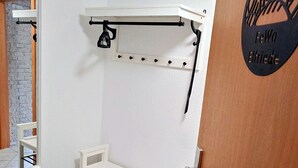 A room with a white bench, a wall-mounted rack, a mirror, and a door with a logo.