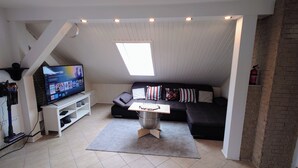 A loft-style living room with a television, sofa, and a small table.
