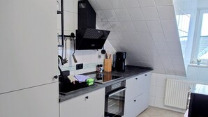 A modern kitchen with white cabinets, a black countertop, and a built-in oven.