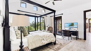 A bedroom with a four-poster bed, a desk, a chair, and a television.