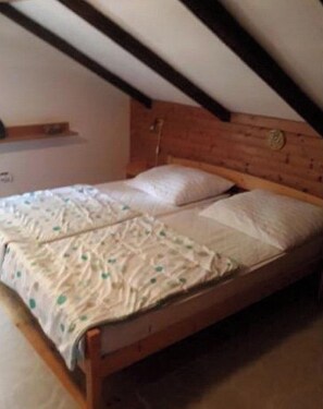 Una cama individual con cabecera de madera en una habitación con techos inclinados.