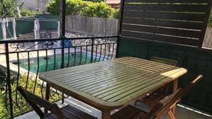 Ein Holztisch und Stühle auf einem Balkon mit Blick auf ein Schwimmbad.