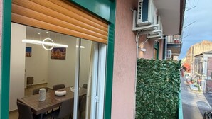 A dining area with a table and chairs, a sliding glass door, and an air conditioning unit on the exterior wall. - Elled-home (Misterbianco)