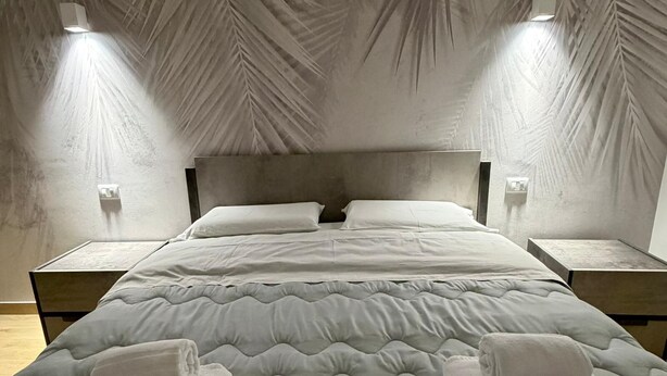 A bedroom with a bed, two bedside tables, and a ceiling with a leaf pattern. - Elled-home (Misterbianco)