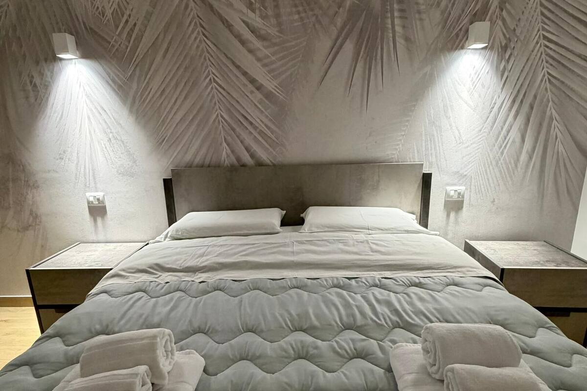 A bedroom with a bed, two bedside tables, and a ceiling with a leaf pattern.