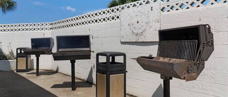A row of barbecue grills against a white wall with a lattice design.