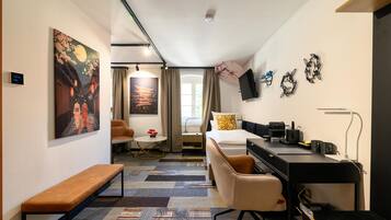 Een hotelkamer met een bed, bureau, stoel en kunstwerken aan de wanden.