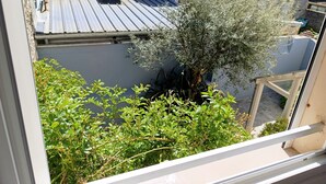 Blick auf ein Gebäude mit Metallbedachung, einen Baum und umgebende Grünflächen.