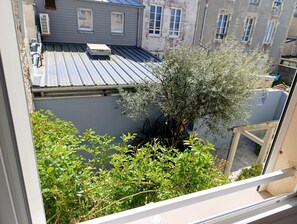 Blick auf ein Gebäude mit Metallbedachung, einen Baum und umgebende Grünflächen.