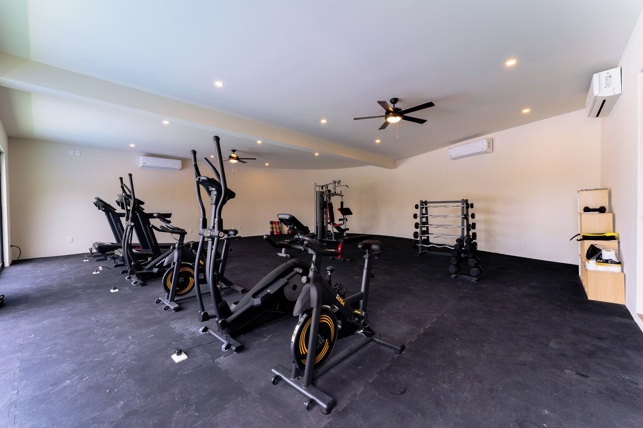 Une salle de sport équipée de divers appareils d’exercice, notamment des tapis de course, des vélos d’appartement et des appareils de musculation.