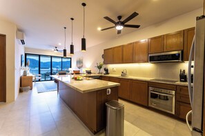 A modern kitchen with wooden cabinets, a stainless steel refrigerator, and a large island with a sink. - 2BDR Santa Cruz Main Level | Walk to Beach & Town (Huatulco)