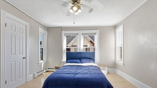 Una camera da letto con un letto, una ventola a soffitto e una finestra vista.