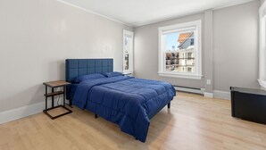 Camera da letto con un letto, un comodino, una finestra e vista sugli edifici.