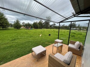 Une terrasse extérieure aménagée avec des meubles en osier, offrant une vue sur un champ verdoyant.