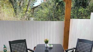 Una terrazza con tavolo e quattro sedie, circondata da una pergola in legno e un recinto bianco.