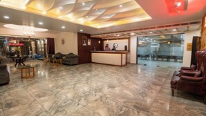 Un hall de hotel con mostrador de recepción, zona de estar y un amplio ventanal.