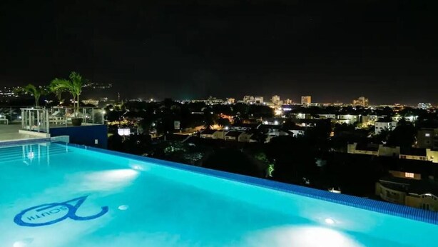 A nighttime view of a swimming pool with a cityscape in the background. - City Apartment in Kingston AC with Pool (Kingston)