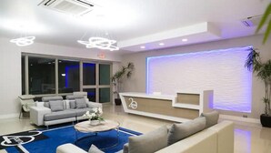 A modern hotel lobby with a reception desk, sofas, a coffee table, and a large window. - City Apartment in Kingston AC with Pool (Kingston)