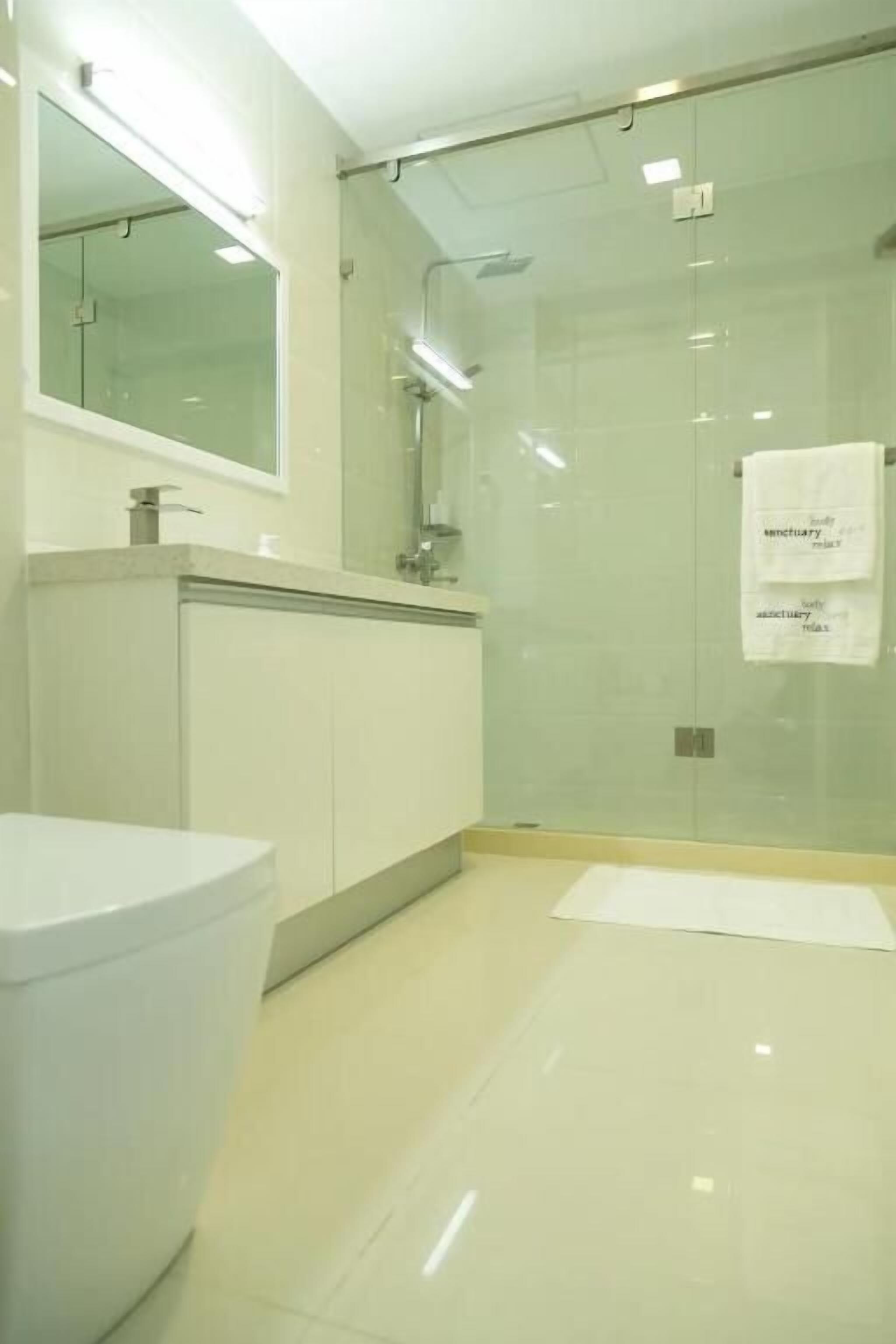 A modern bathroom with a glass shower enclosure, a white sink, and a mirror above the sink.