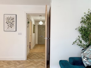 Un couloir doté d’un plancher en bois, une porte donnant sur une autre pièce et une estampe botanique encadrée accrochée au mur.
