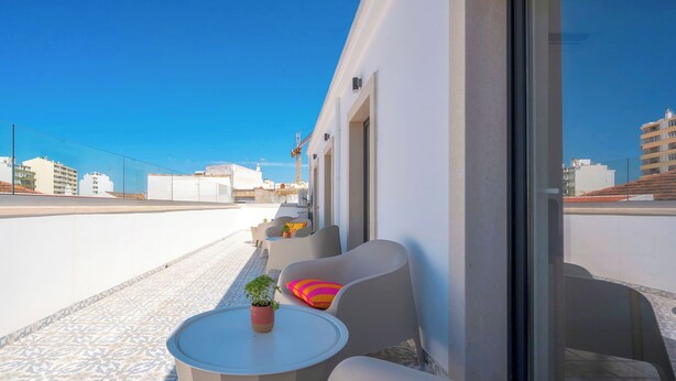 A rooftop terrace with a white wall, a glass door, and a potted plant. - Marina Legacy I Boutique Residence (Faro)