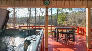 A covered outdoor area with a hot tub, a table, and chairs. - Up to Par in Hot Springs Village, AR (Hot Springs Village)