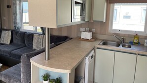 Pieni, käytännöllinen keittiönurkkaus, jossa on mikroaaltouuni, leivänpaahdin ja pesuallas.