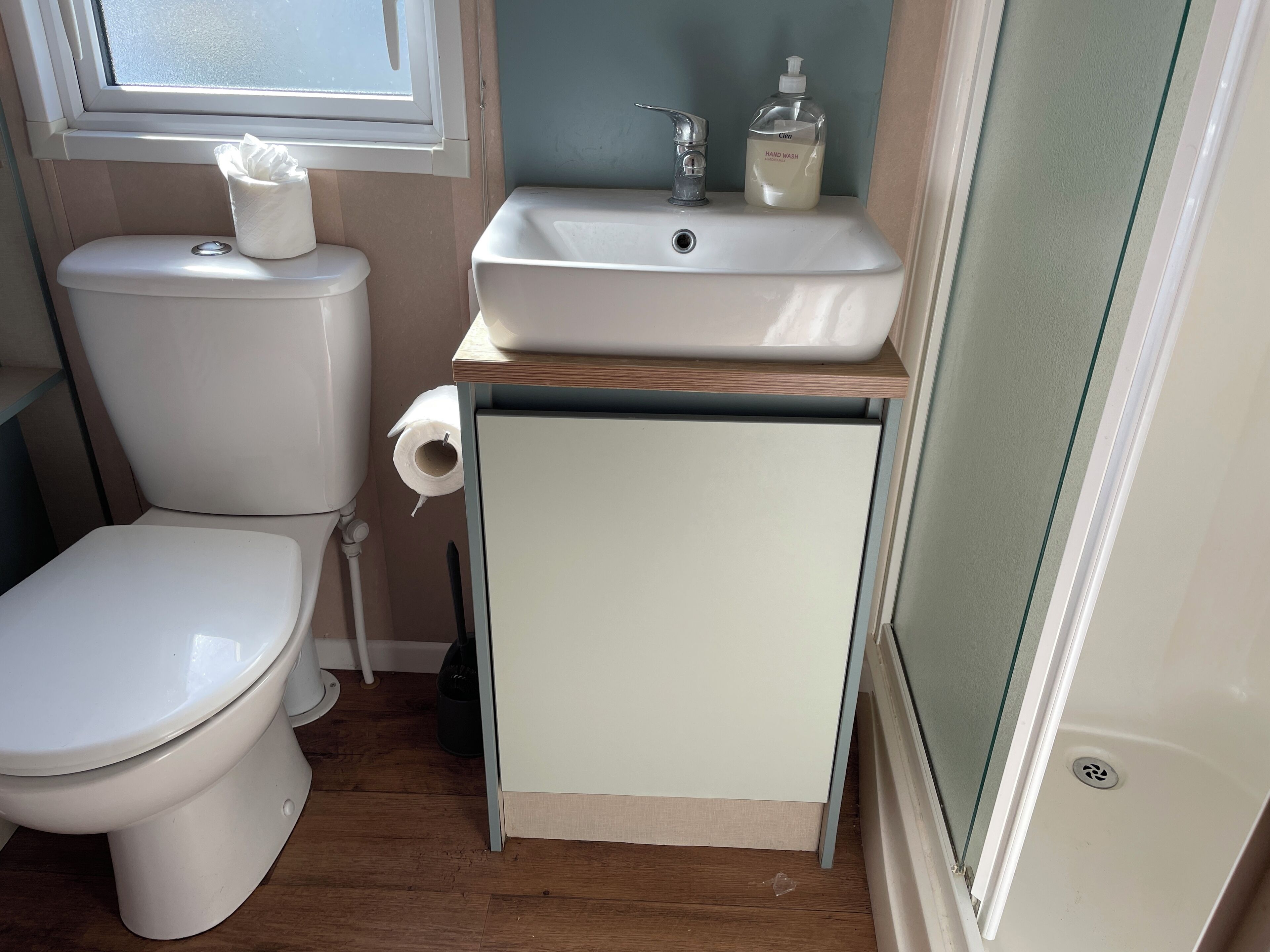 Ein kleines Badezimmer mit Toilette, Waschbecken und einem kleinen Schrank.