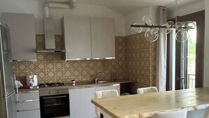 A modern kitchen with a central island, white cabinetry, a patterned backsplash, and a dining area with white chairs. - House of sails in the bay of sails (Valmadrera)