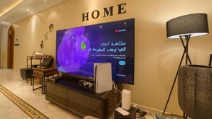 Una sala de estar moderna con un televisor de pantalla plana grande, un sofá, una mesa de centro y una lámpara.
