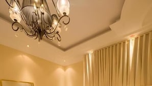 Habitación de hotel con una cama grande, una mesita de noche, un espejo y una araña.