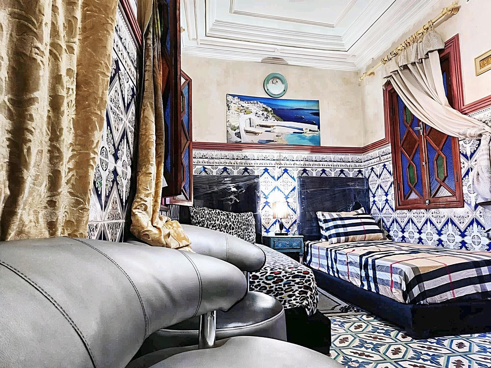 Ein Zimmer mit einem Bett, einem Schlafsofa, Wandmustern und einem Gemälde einer Küstenlandschaft.