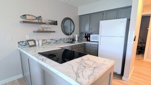 A modern kitchen with a marble countertop, built-in appliances, and a small island.