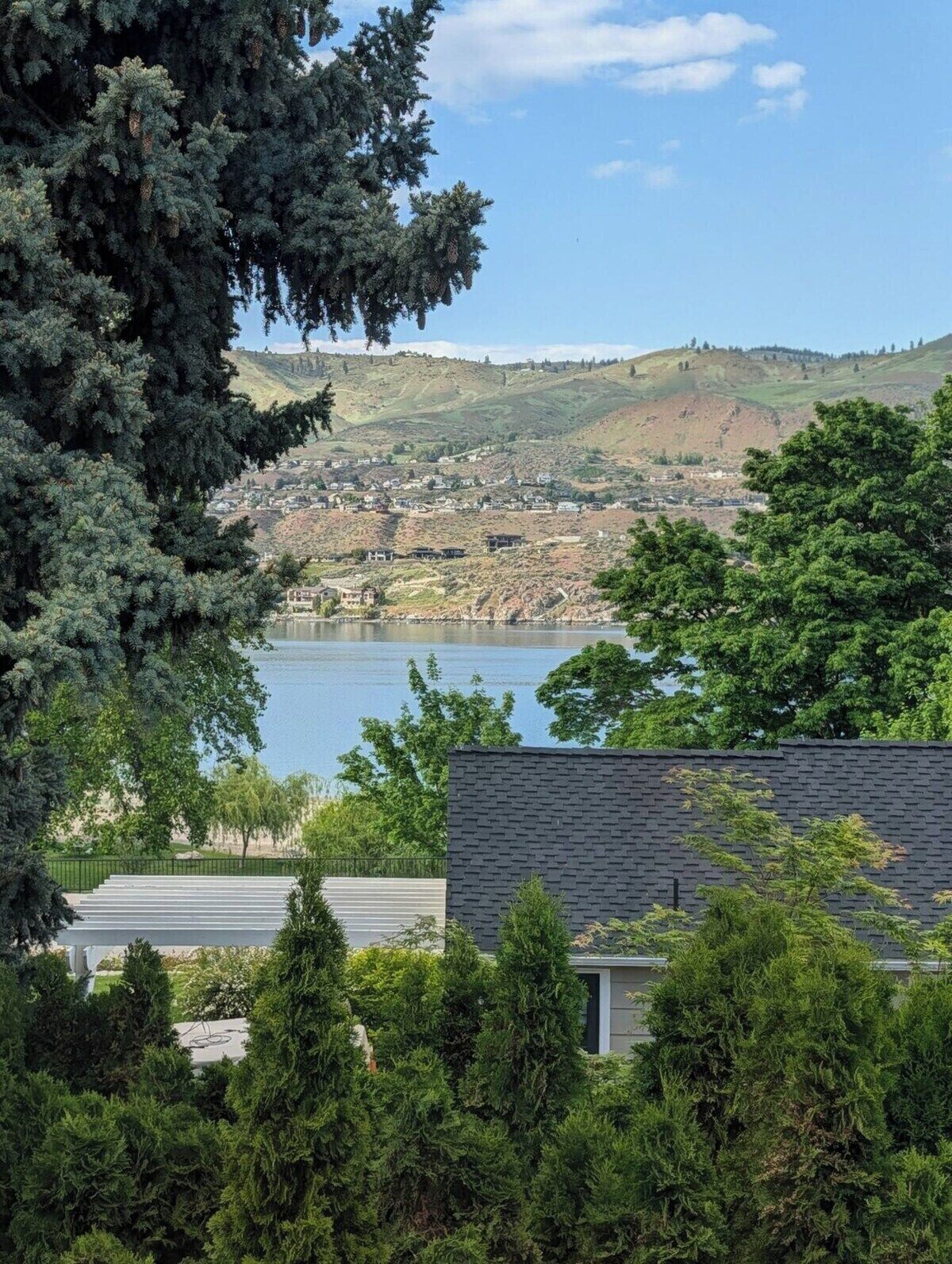 A residential area with a view of a lake, surrounded by hills and trees.