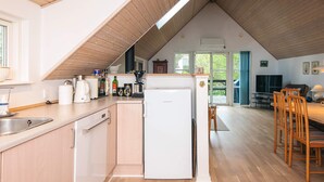 Une cuisine équipée d’un réfrigérateur, d’un évier et de meubles de rangement en bois. On y trouve également un coin repas avec des chaises et une table.