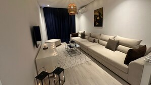 Un salon moderne avec un canapé, une table basse, un téléviseur et un tableau accroché au mur.