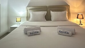Une chambre d’hôtel avec un lit, deux oreillers, une tête de lit, un tableau au mur et deux lampes de chevet.