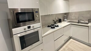 Une cuisine moderne équipée d’un four à micro-ondes encastré, d’un four traditionnel et d’une machine à café posée sur le plan de travail.