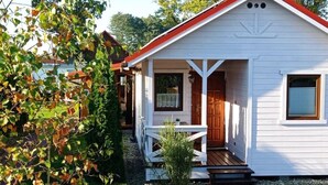 A white building with a red roof, a porch, and a wooden door. - Ferien Bobolin Ferienhäuser by Interhome (Dabki)